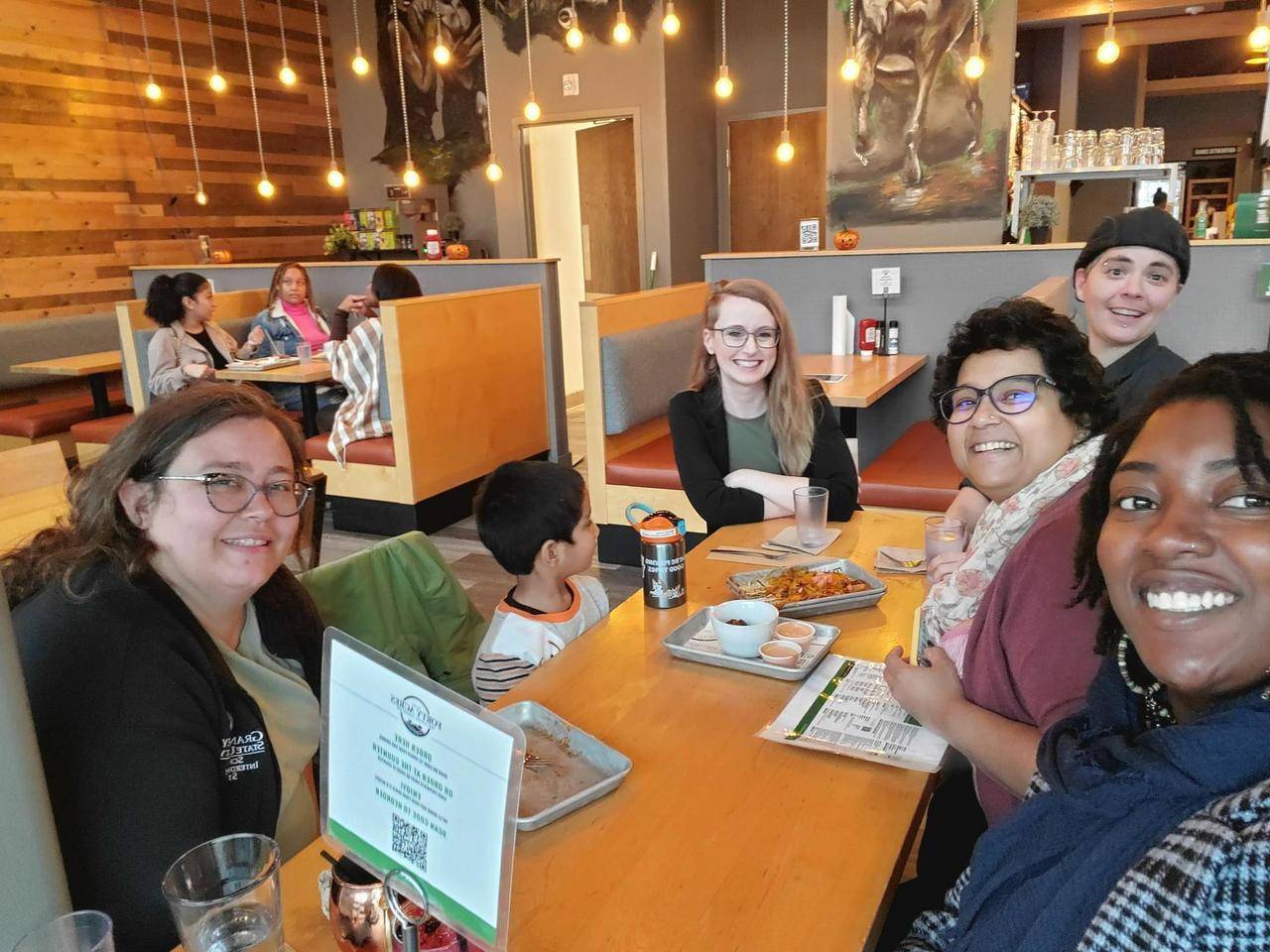 A group of people smiling for a picture at a restaurant table